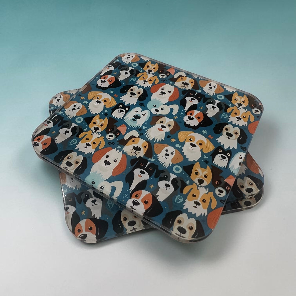 Three square coasters with rounded corners stacked slightly offset, featuring a colorful cartoon dog pattern on a dark blue background, set against a light blue gradient backdrop.