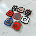 Eight Instagram social media tags arranged on a white marble surface. Each charm has a rounded square body with a small loop at the top to put on a keychain.  Shown in various color combinations including red, black, silver, rose gold, blue and grey.