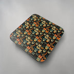 A coaster with rounded corners, featuring a repeating pattern of cute cartoon cats in orange, yellow, and teal on a neutral light gray surface.
