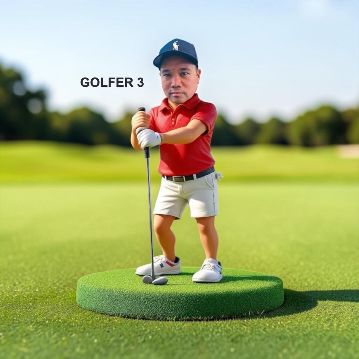 A golfer stands on a green circular base on a golf course. The golfer wears a navy cap with a white logo, a red polo shirt, white shorts, and white shoes, and is holding the golf club down. Style Golfer 3.