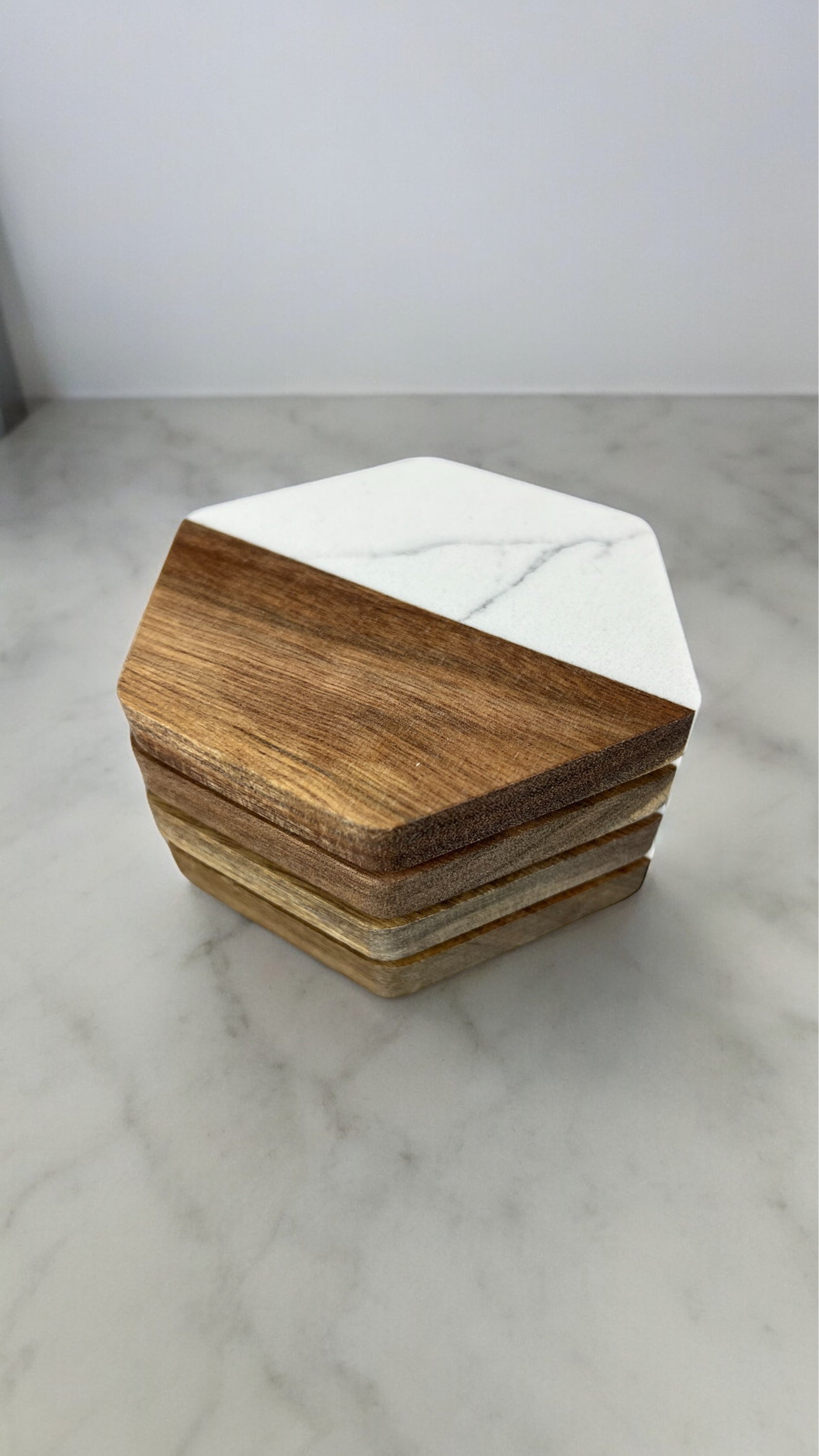 A stack of 4 hexagonal coasters displayed on a white marble surface.
