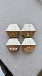 Four hexagon wooden and marble coasters arranged on a gray surface. 
